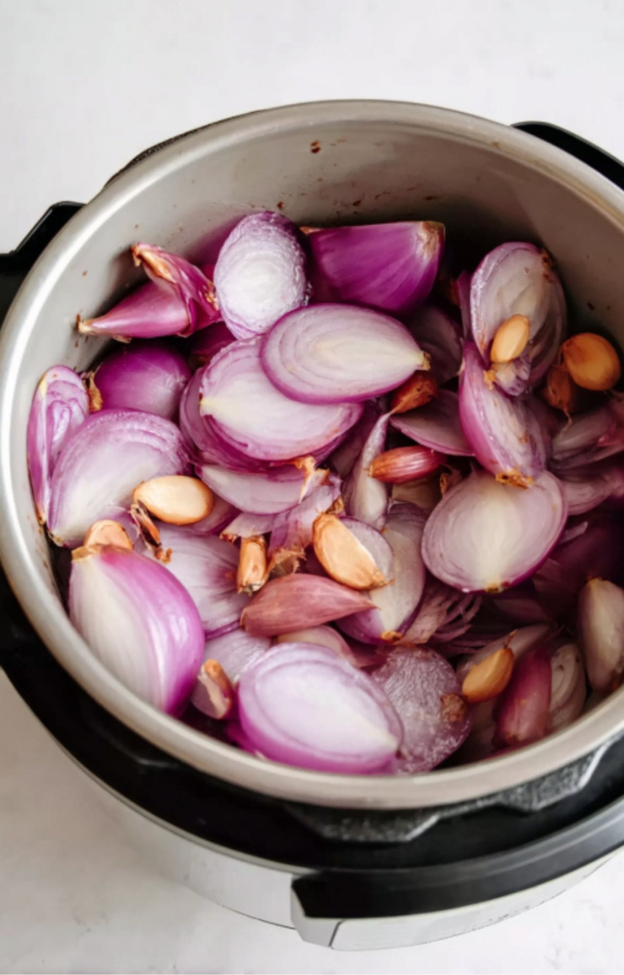 Instant Pot filled with sliced red onions and garlic, being sautéed as the base for Mississippi Pot Roast.