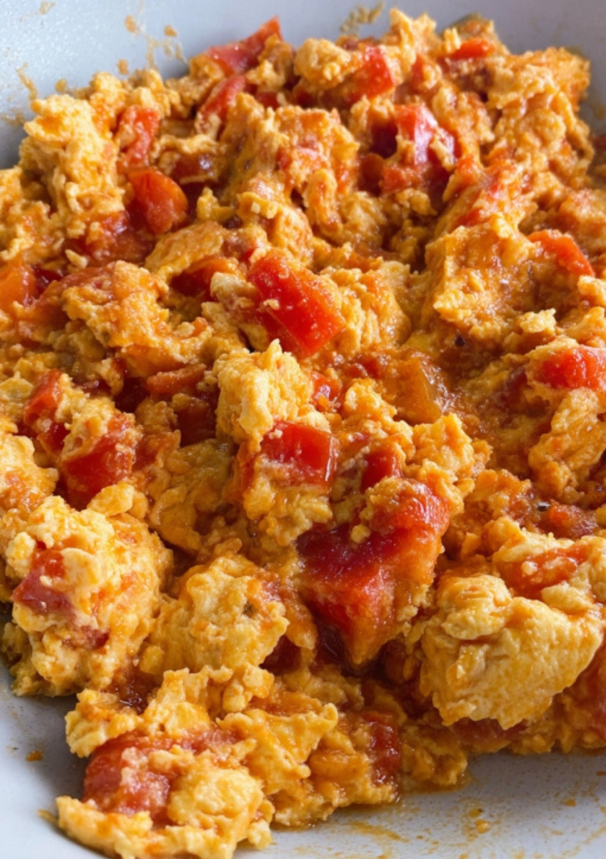 Close-up of Nigerian-style egg sauce with scrambled eggs, tomatoes, and red peppers in a pan.
