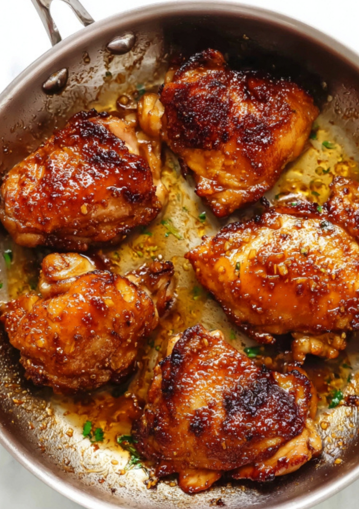Chicken thighs browning in a pan, covered with a rich soy glaze, ready to be coated and served.