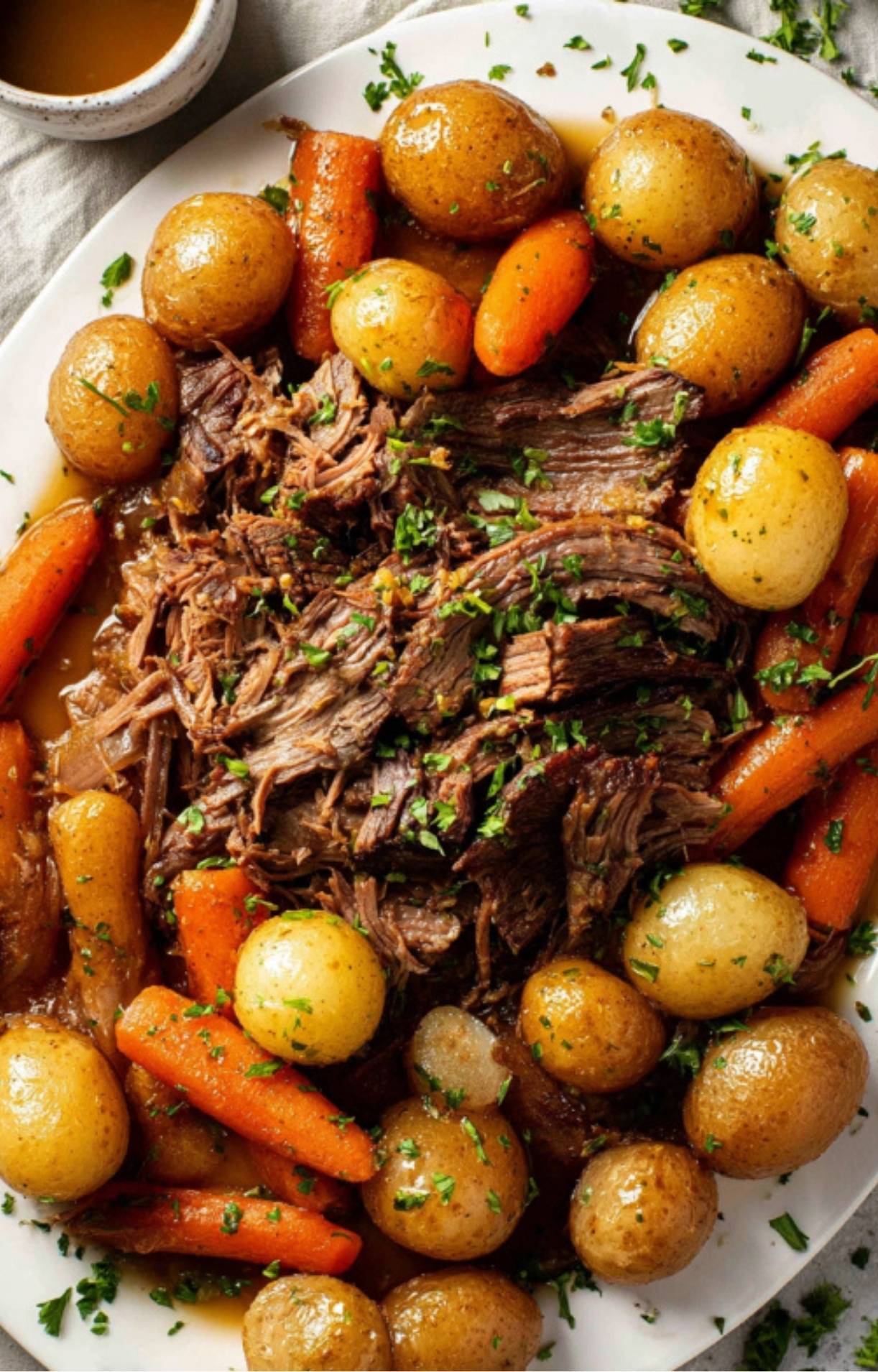Platter of crockpot roast beef, carrots, and potatoes, ready to serve for an easy weeknight family dinner or Sunday supper.
