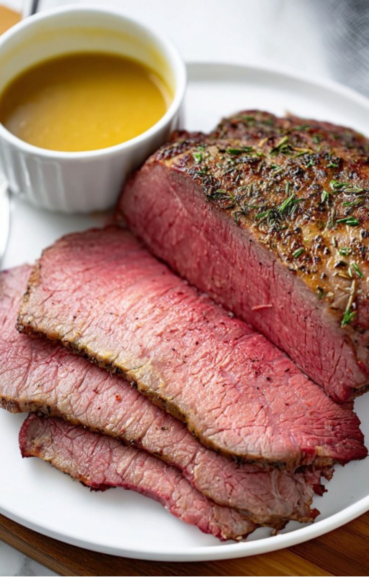 Perfectly cooked sirloin tip roast sliced thin on a white plate with savory beef gravy