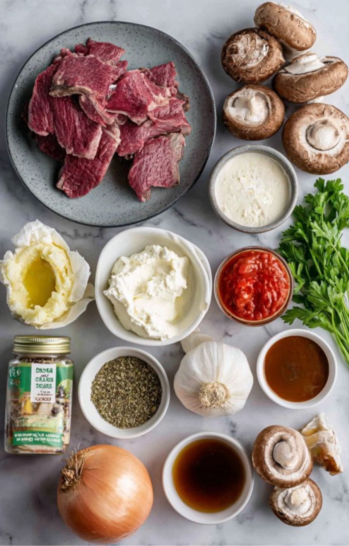 Flat lay of sliced roast beef, fresh mushrooms, parsley, garlic, onions, spices, tomato, and crème fraîche—everything you need for beef stroganoff.