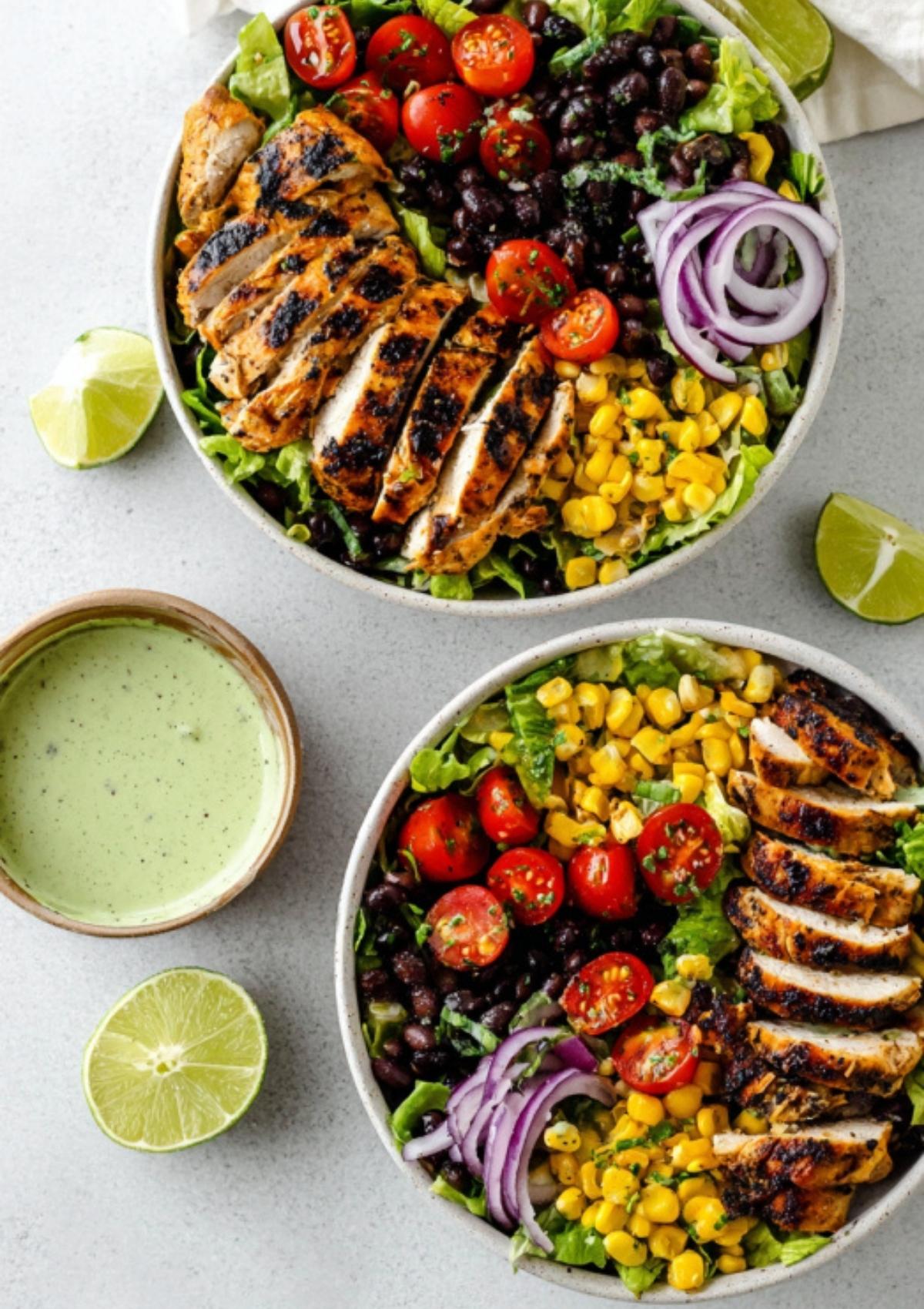 Two bowls of Southwest Chicken Salad with grilled chicken, black beans, corn, tomatoes, red onion, and creamy avocado dressing