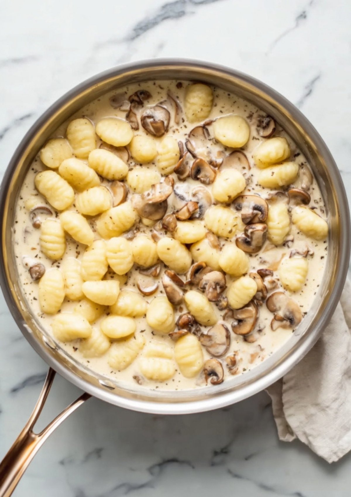 Pan of fluffy gnocchi and sliced mushrooms simmering in a creamy garlic Parmesan sauce. Fast and filling comfort food for busy nights.