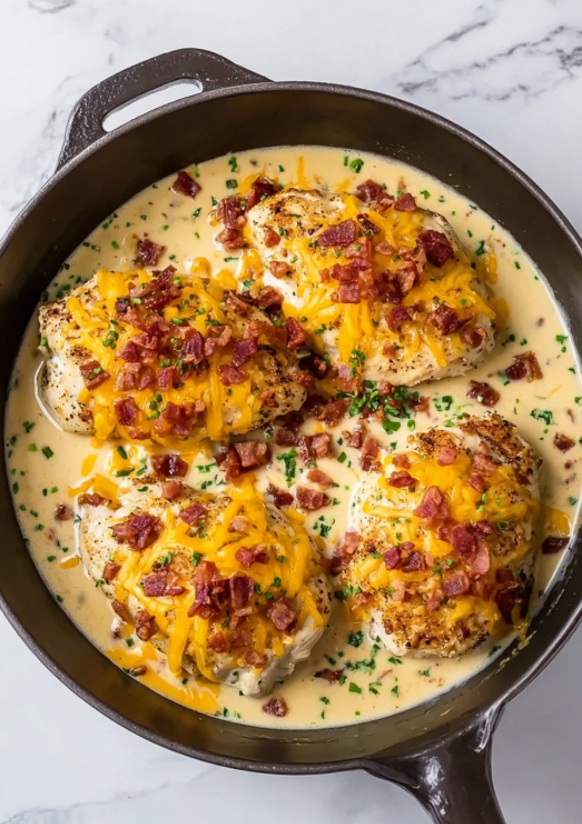Overhead view of bacon ranch chicken bake with cheddar cheese, crispy bacon, and fresh herbs in a skillet, perfect for family dinners and meal prep.