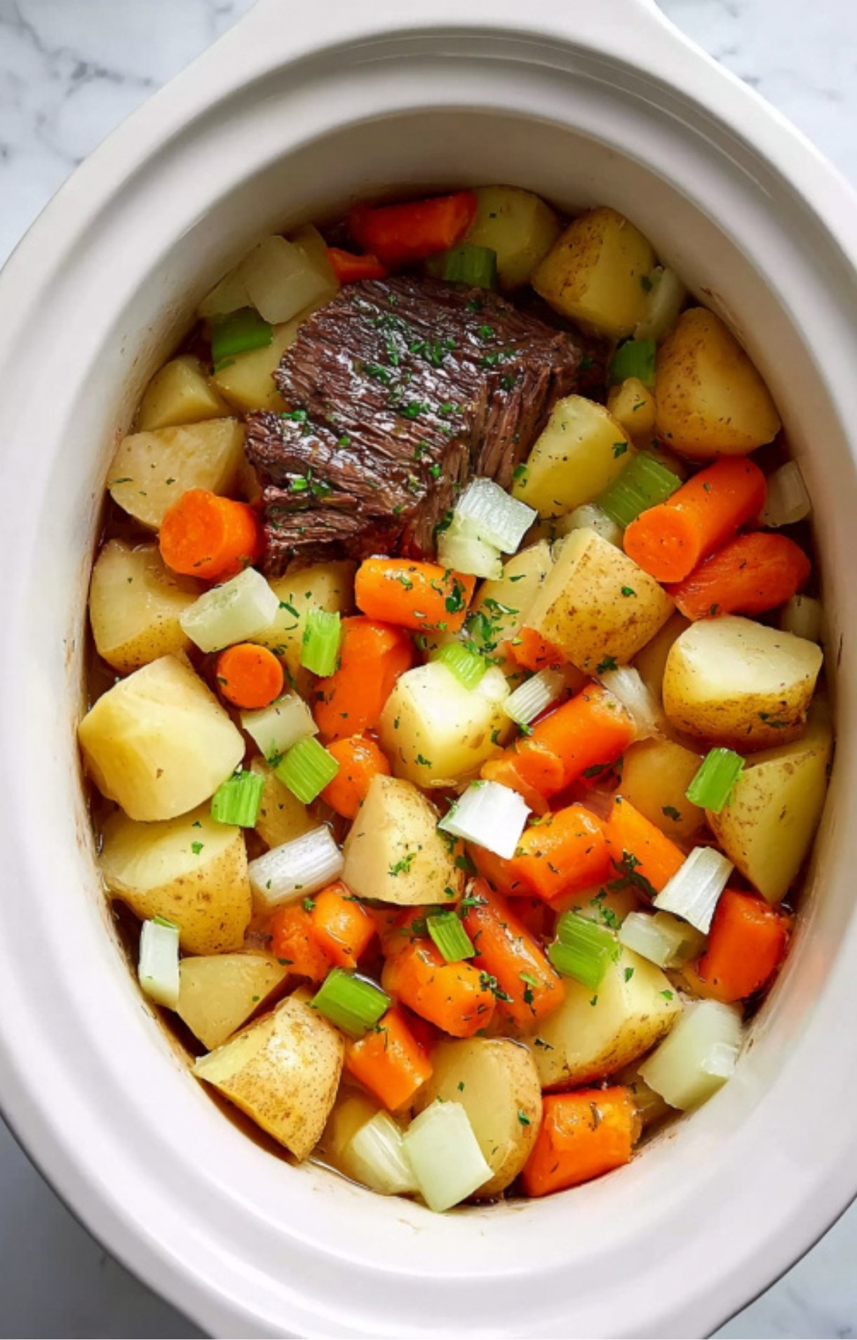 Tender slow cooker pot roast with potatoes, carrots, celery, and onions for a cozy family dinner.