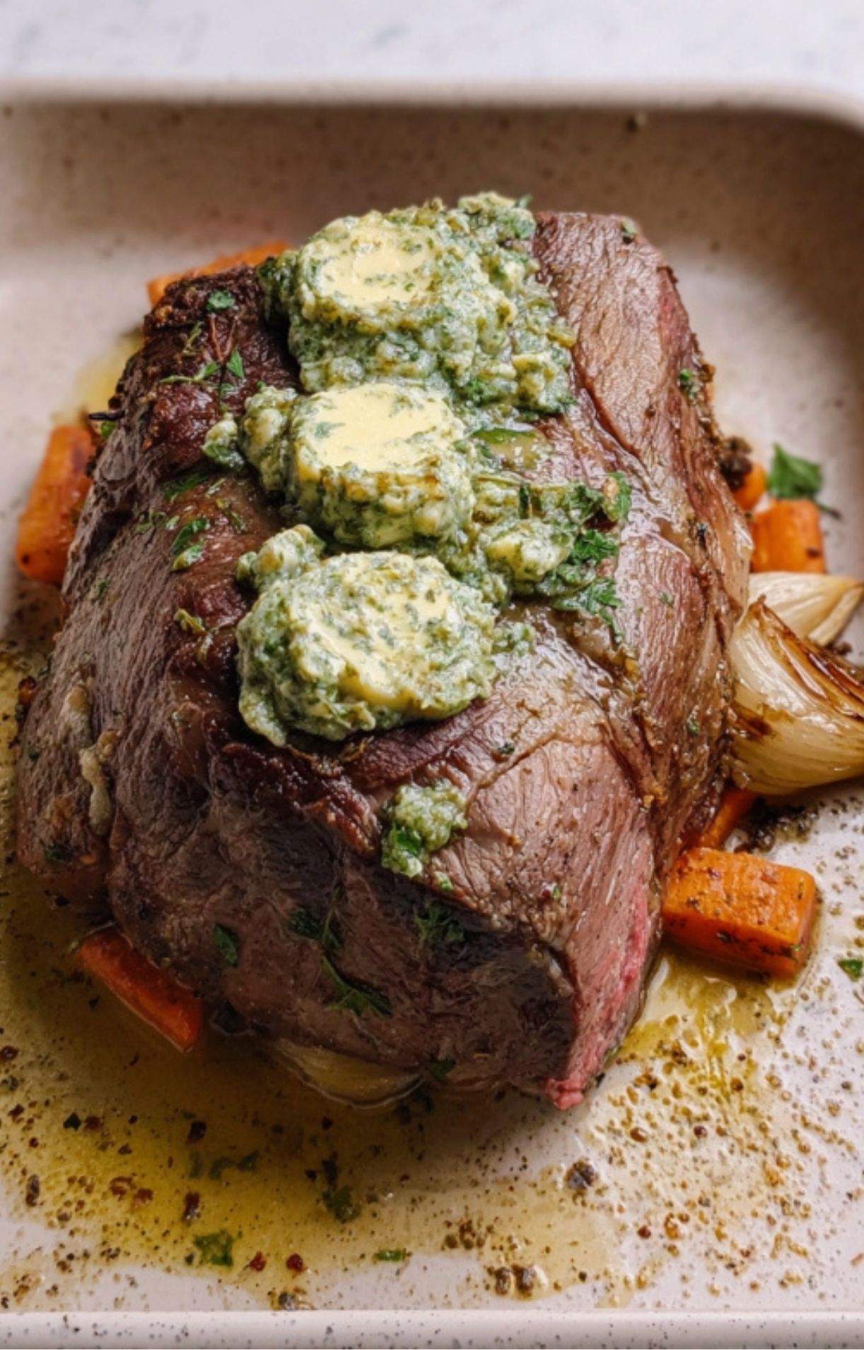 Cooked eye of round roast topped with melting herb compound butter and served with roasted vegetables.