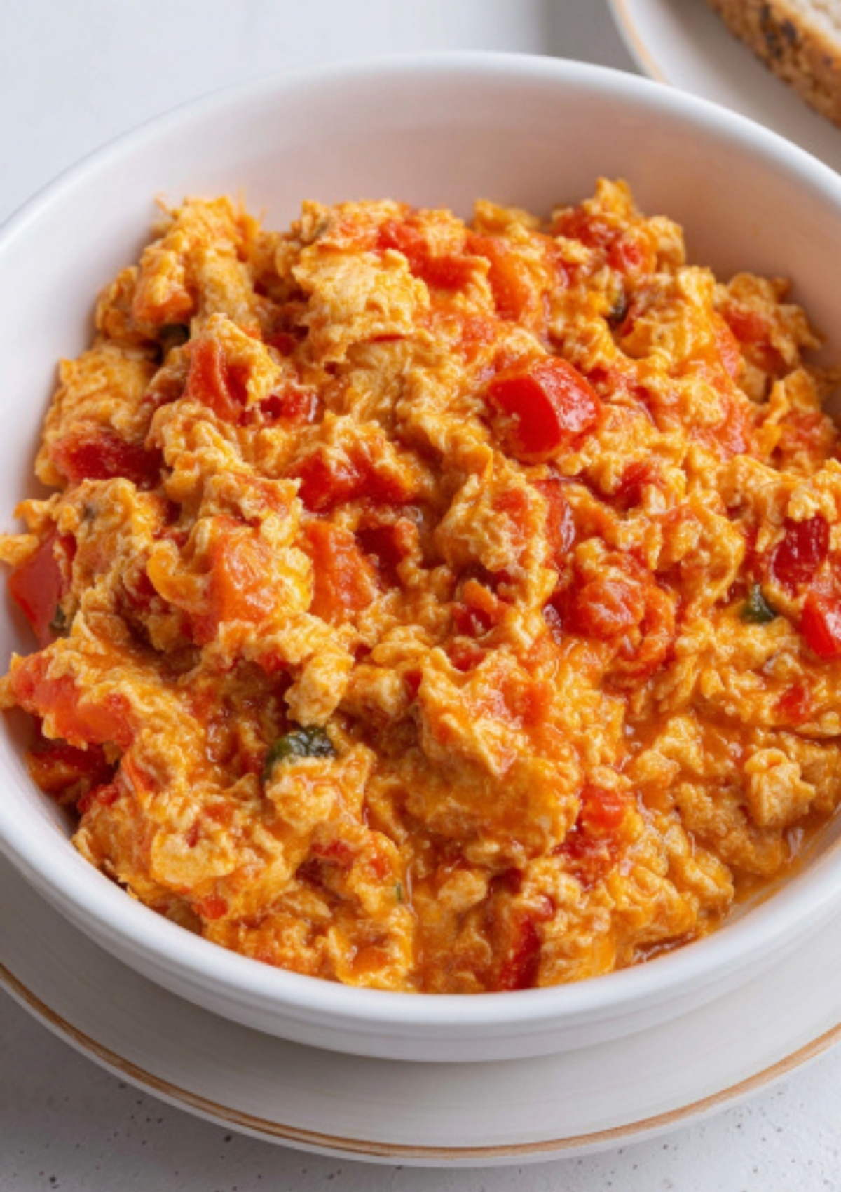Nigerian-style scrambled egg sauce with tomatoes and peppers in a white bowl, side angle.