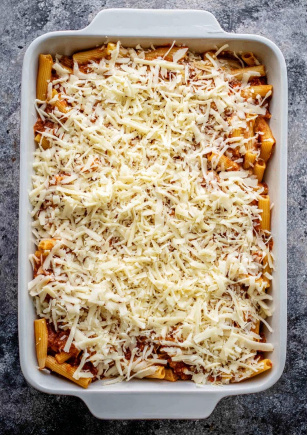 Unbaked ziti casserole topped with shredded mozzarella and ready for the oven.