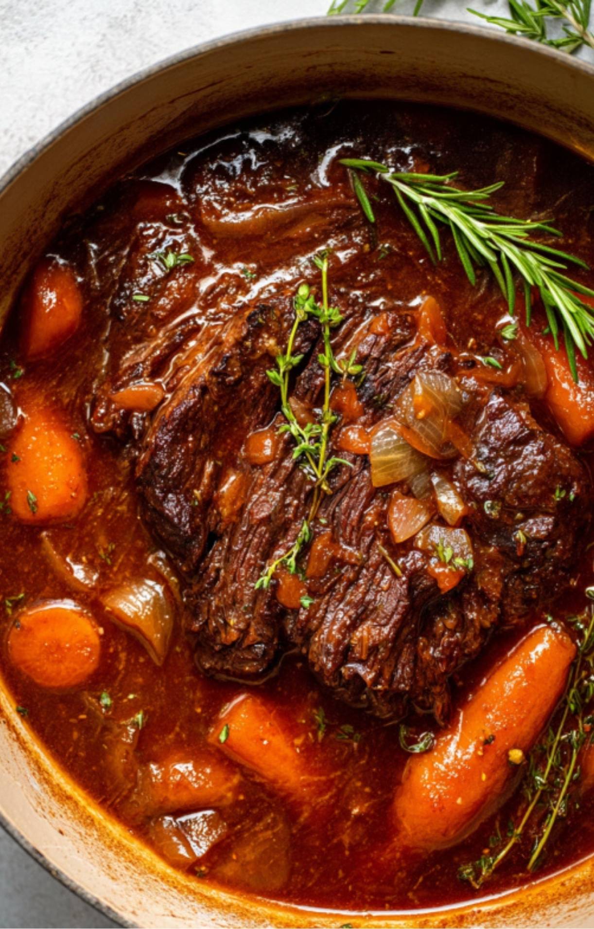 Pot roast simmering with carrots, celery, and fresh herbs in a Dutch oven—classic comfort food made easy.