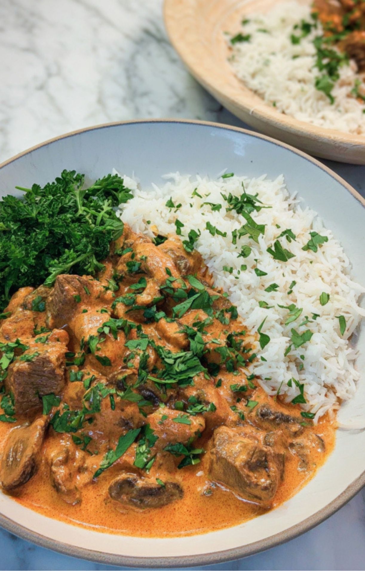 Bowl of creamy leftover roast beef stroganoff alongside steamed rice and fresh parsley, perfect for a hearty dinner.