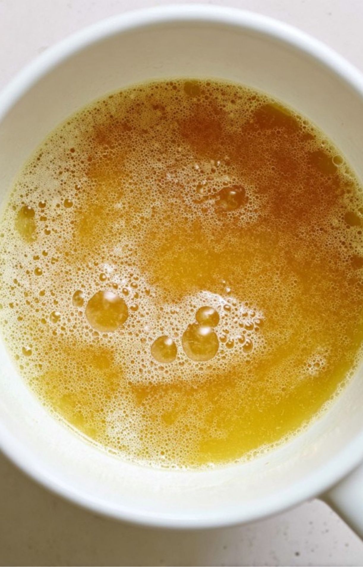 A bowl of golden beef broth with a rich, savory surface, perfect for making gravy or soups