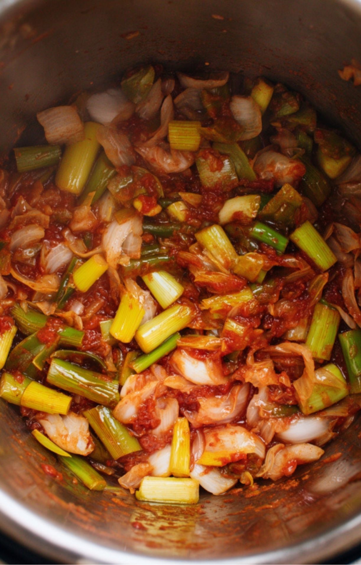 Diced onions, leeks, celery, and tomato paste sautéing in an Instant Pot