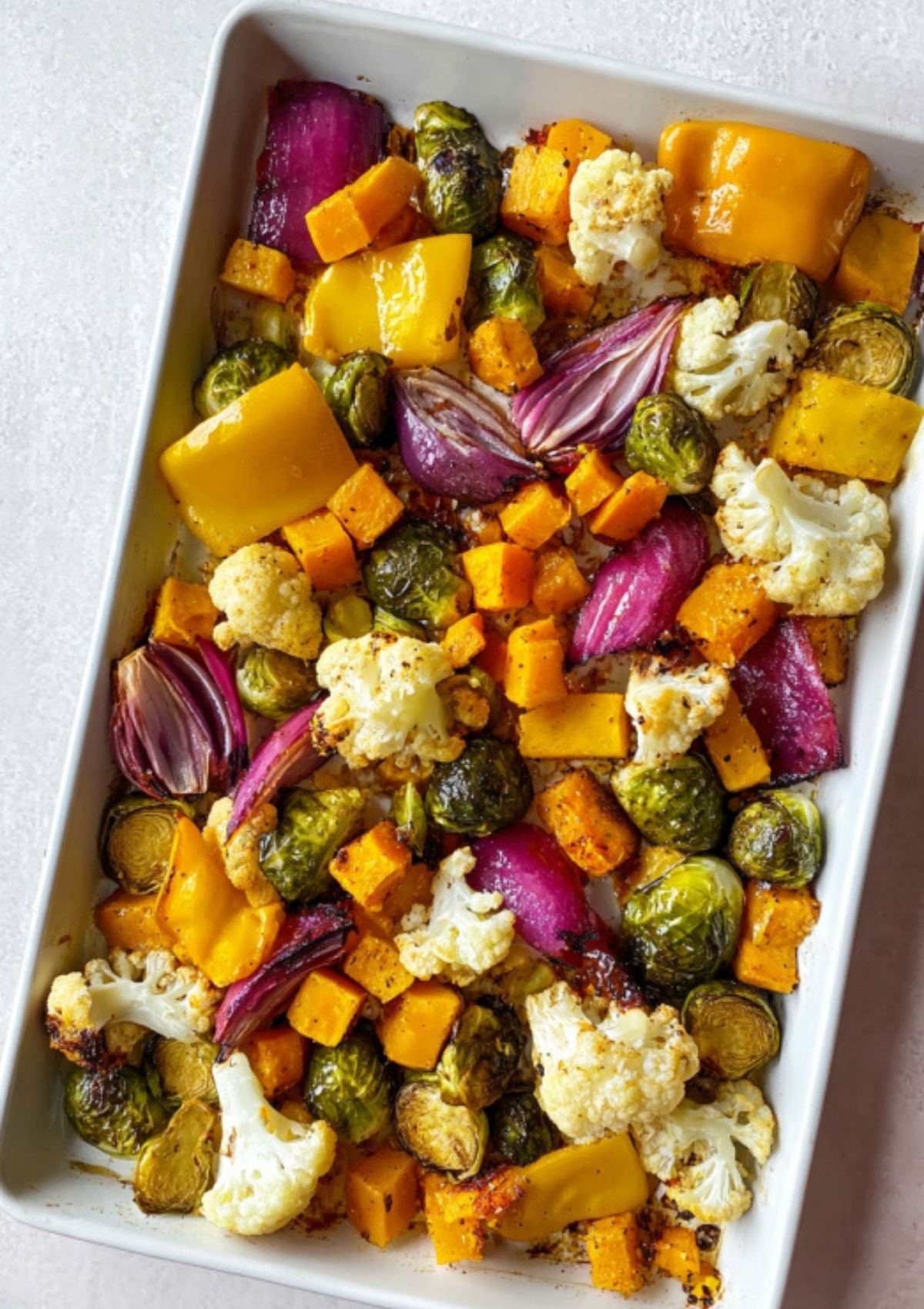 Sheet pan loaded with roasted brussels sprouts, cauliflower, red onion, yellow bell pepper, and butternut squash, perfectly caramelized.