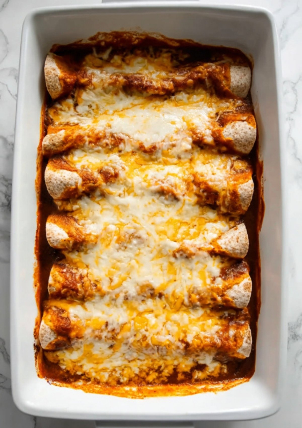 Baked black bean enchiladas with melted cheese in a white casserole dish, ideal for a healthy vegetarian dinner or meal prep.