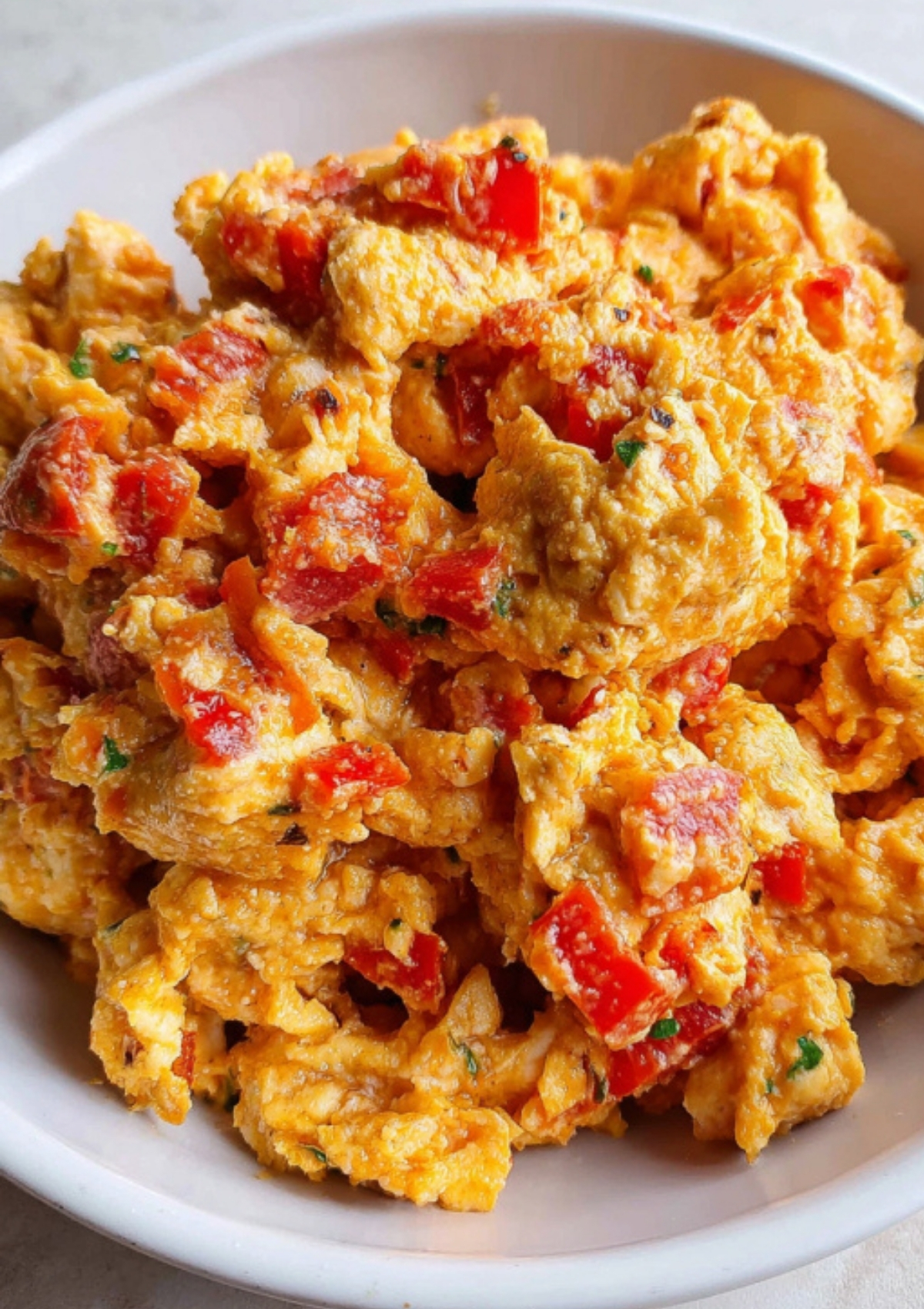 Close-up of Nigerian egg sauce in a white bowl, featuring chunks of egg, tomato, and pepper.