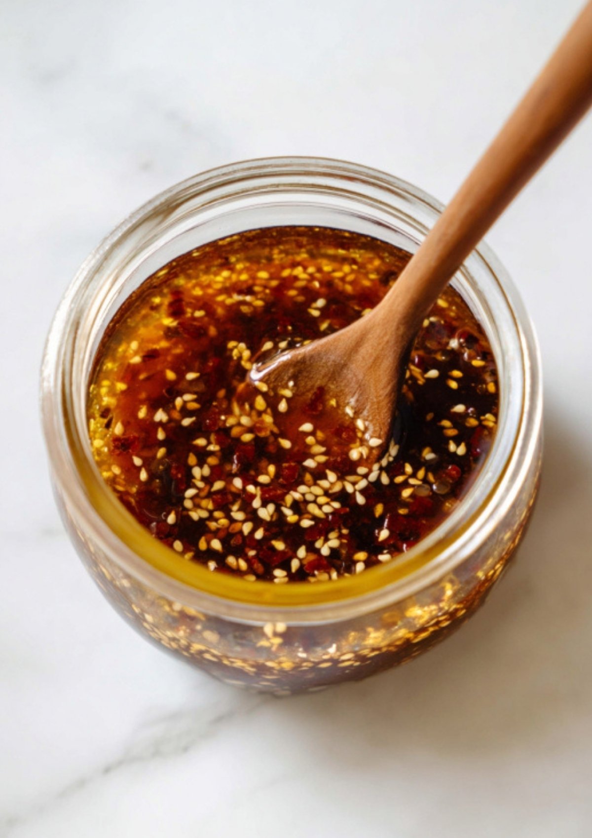 Overhead view of soy ginger sauce in a jar with sesame seeds and a wooden spoon. Great for noodles, salads, and quick weeknight meals.