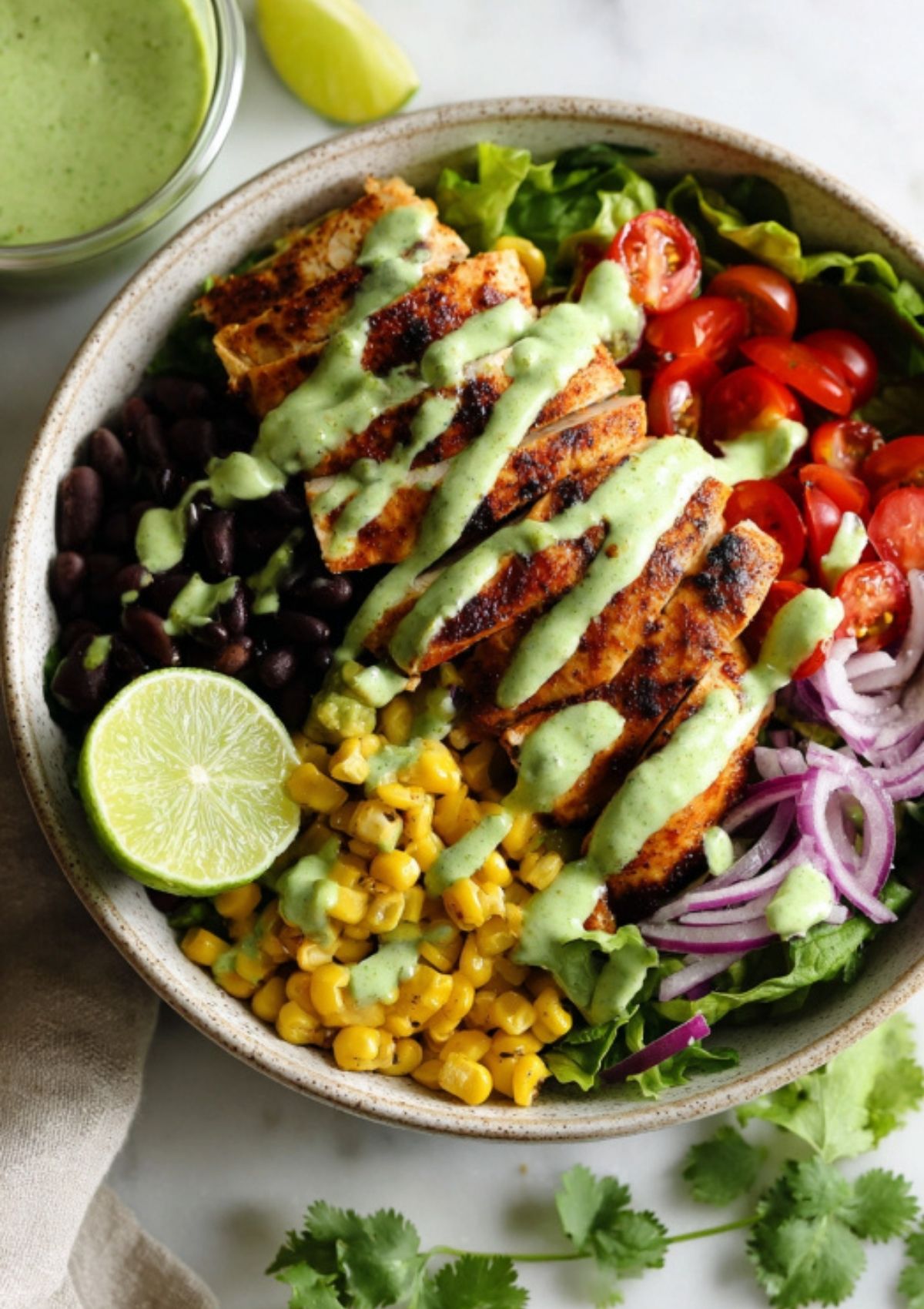 Colorful bowl of Southwest Chicken Salad with grilled chicken, corn, black beans, cherry tomatoes, red onion, and avocado ranch dressing