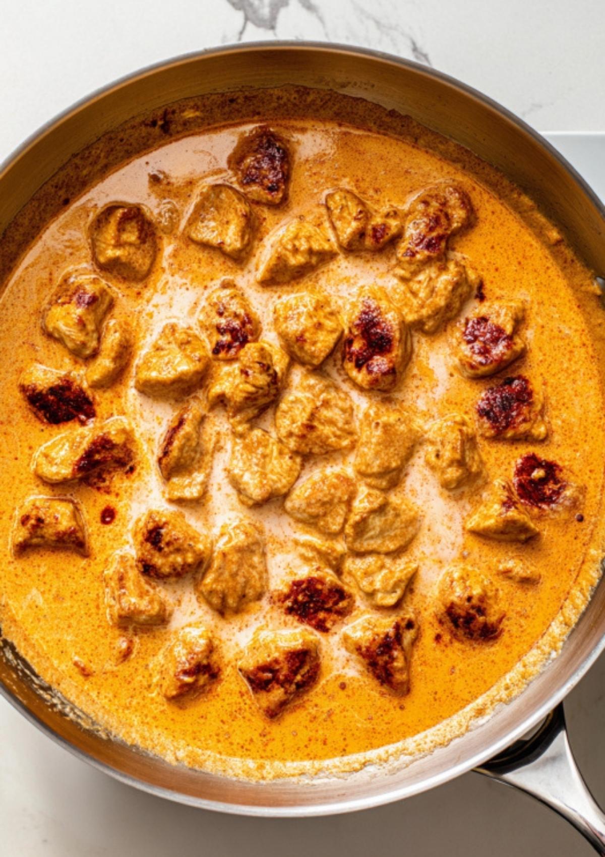 Chicken pieces simmering in a rich, orange-hued creamy fajita sauce, ready for pasta. Best for one-pan chicken dinners and comfort food lovers.