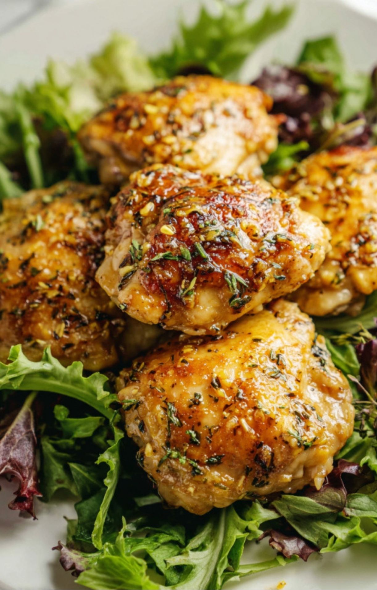 Golden honey mustard chicken thighs served on mixed salad greens for a healthy and easy dinner