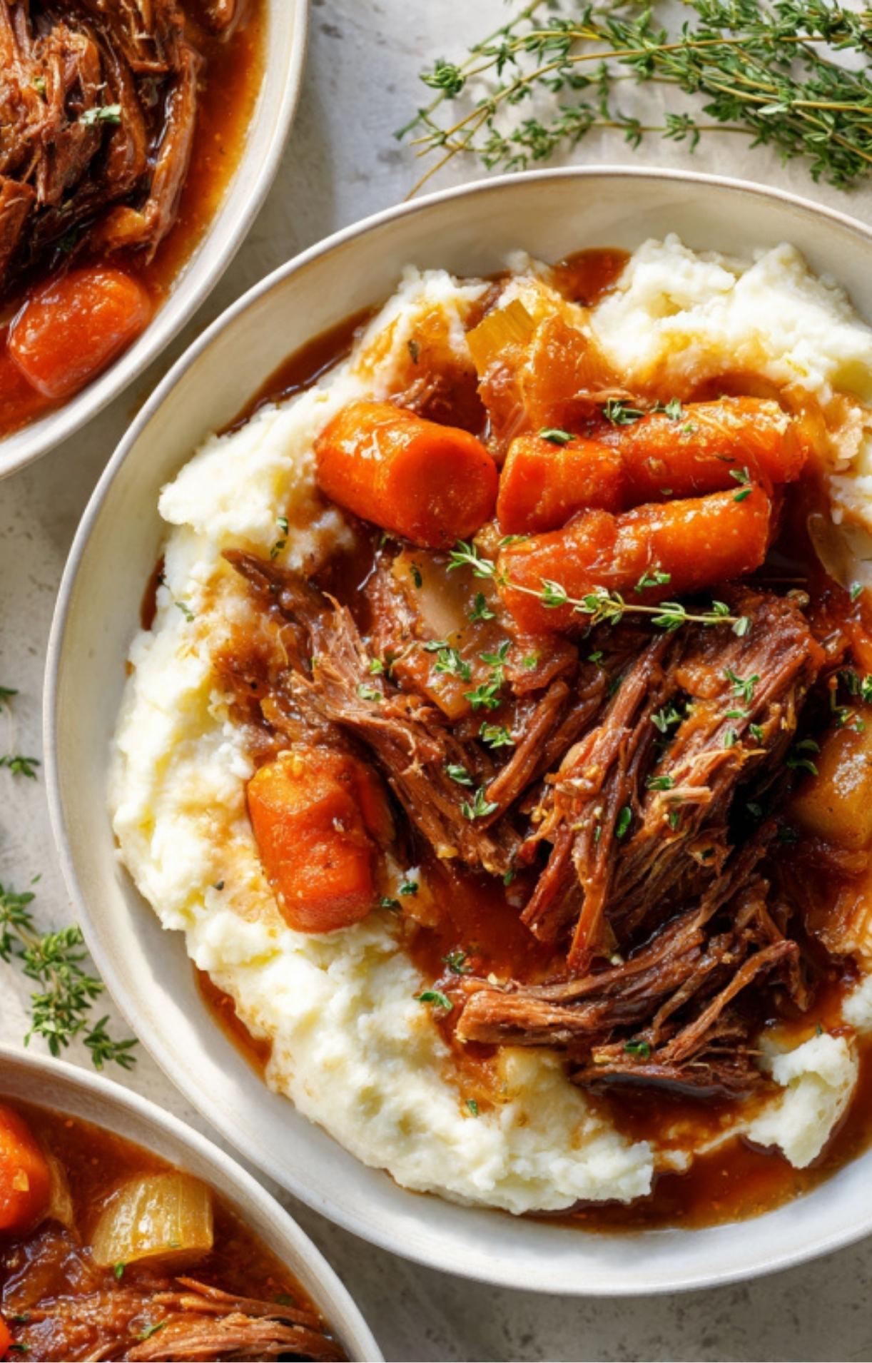 Dutch oven filled with pot roast, carrots, onions, and rich broth, slow-roasted for deep, herby flavor.