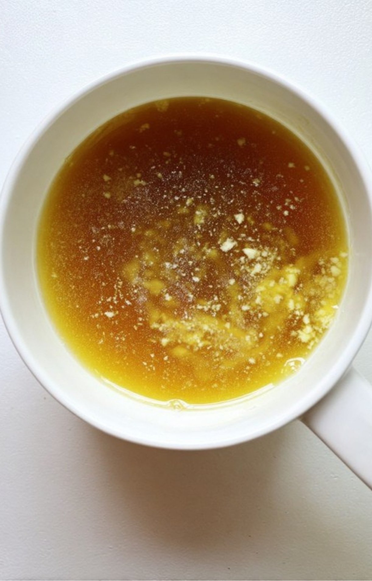 Homemade beef stock gravy with minced garlic in a bowl, ready to serve with classic roast beef