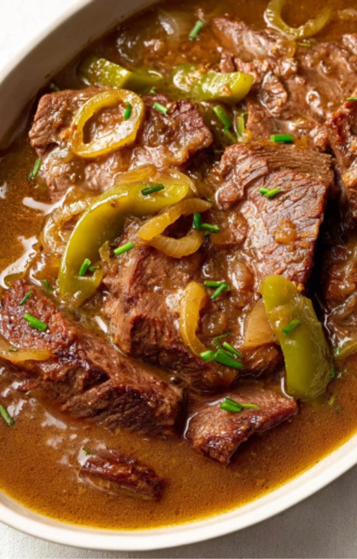 Mississippi Pot Roast served in a white dish, topped with sliced pepperoncini and bell peppers in a rich gravy.