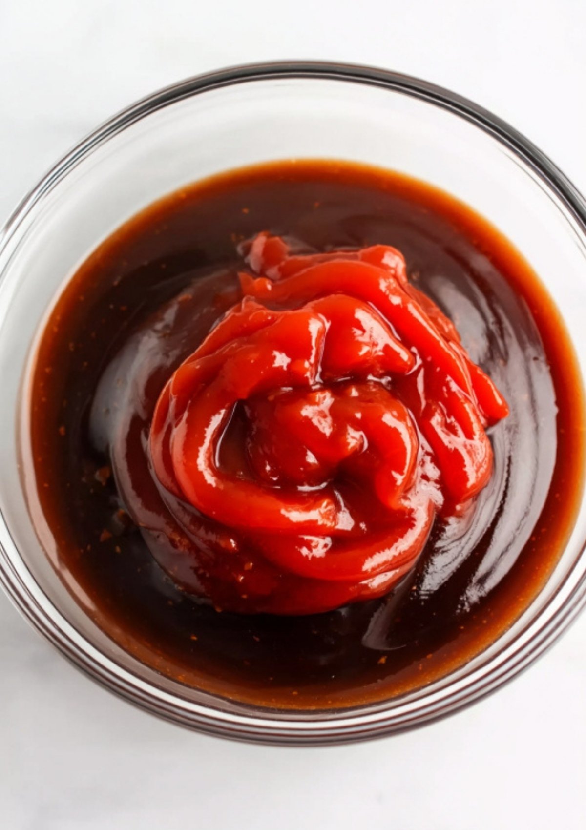 Overhead shot of ketchup and other katsu sauce ingredients in a glass bowl before mixing.