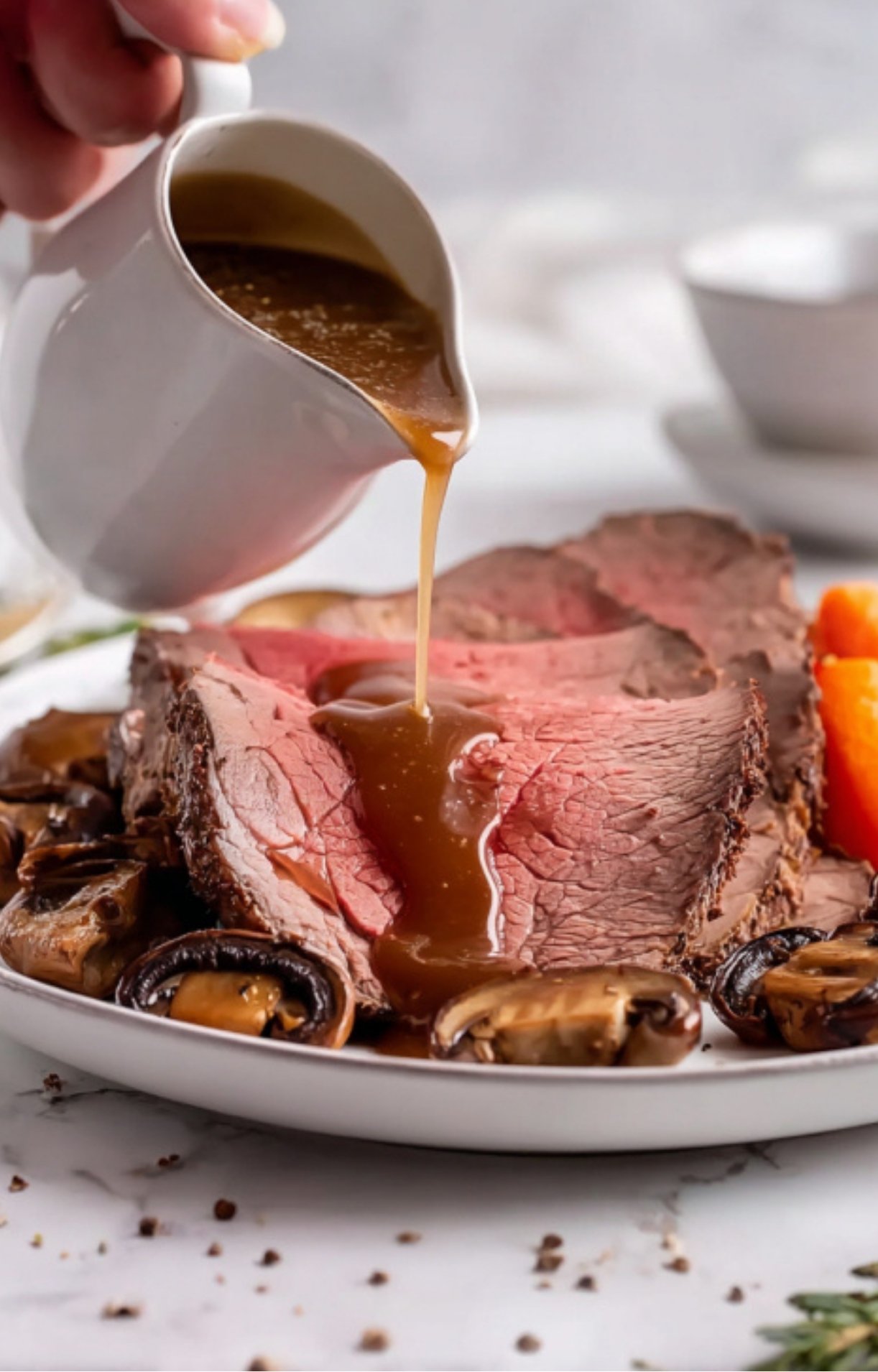 Sliced eye of round roast on a plate topped with rich homemade gravy and served with mushrooms and carrots.
