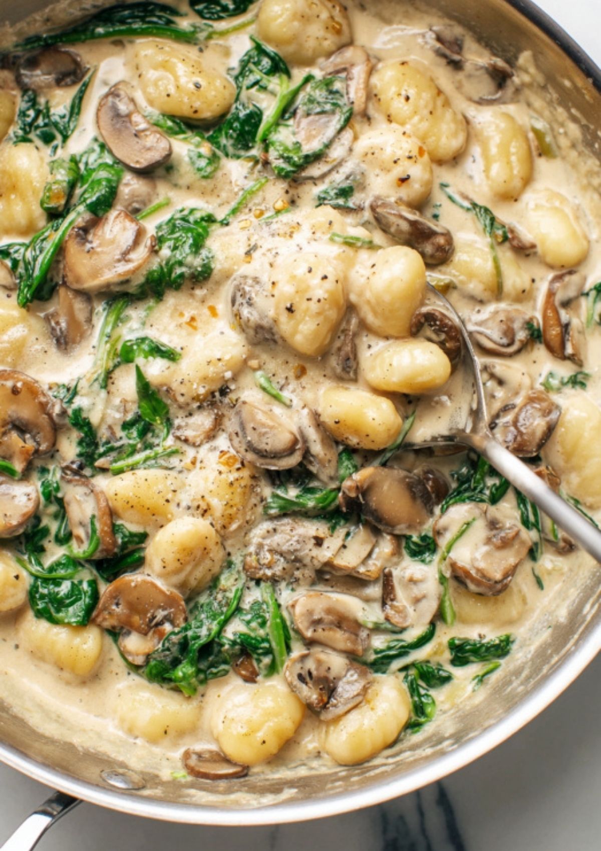 Creamy mushroom gnocchi in a skillet with sautéed mushrooms, fresh spinach, and a rich Parmesan cream sauce. Perfect for weeknight comfort food.