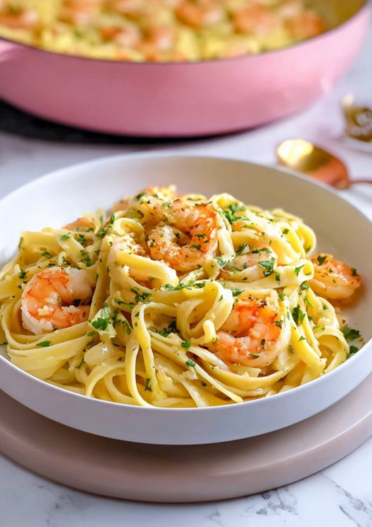 Fettuccine with shrimp, garlic butter, and parsley in a pink skillet