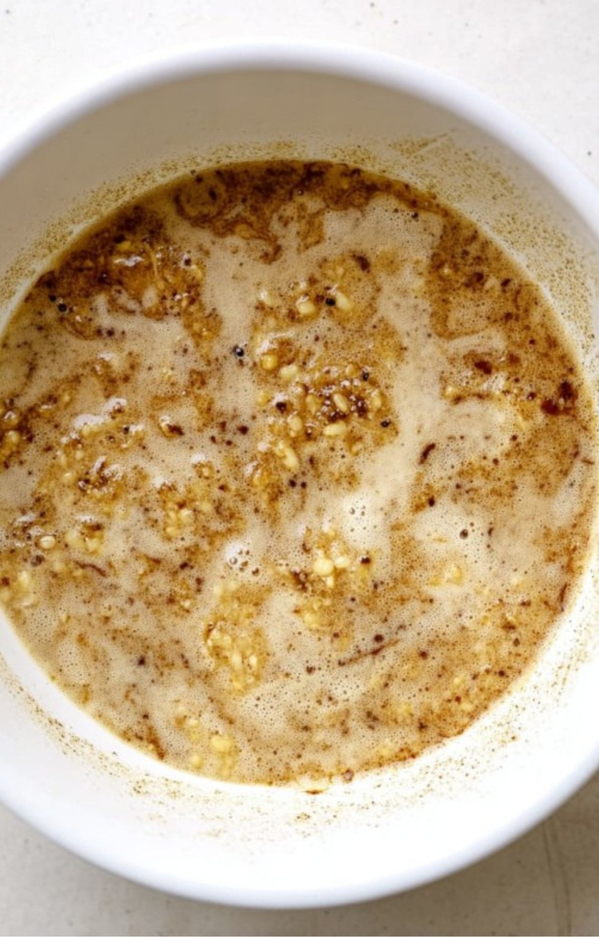 Bowl of garlic butter gravy with seasonings, ideal for drizzling over roasted meats or potatoes