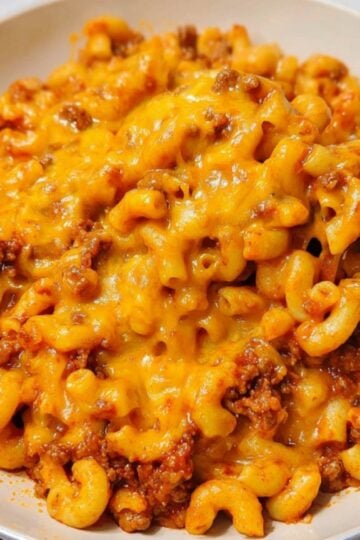 Plate of cheesy goulash with elbow macaroni, ground beef, and golden cheddar cheese. Hot and hearty dinner idea that’s quick, easy, and loved by kids and adults.