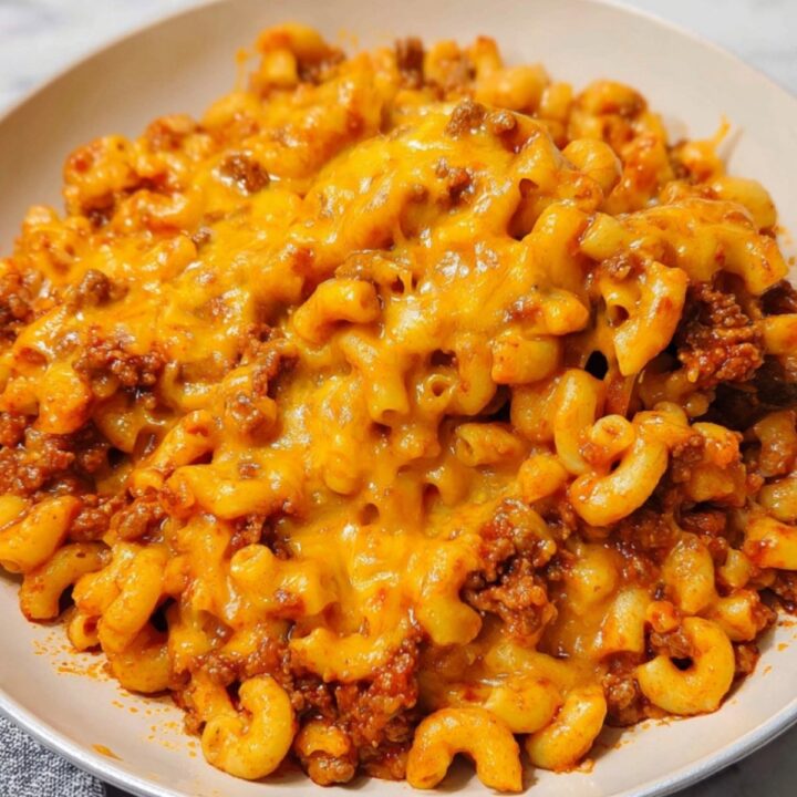 Plate of cheesy goulash with elbow macaroni, ground beef, and golden cheddar cheese. Hot and hearty dinner idea that’s quick, easy, and loved by kids and adults.