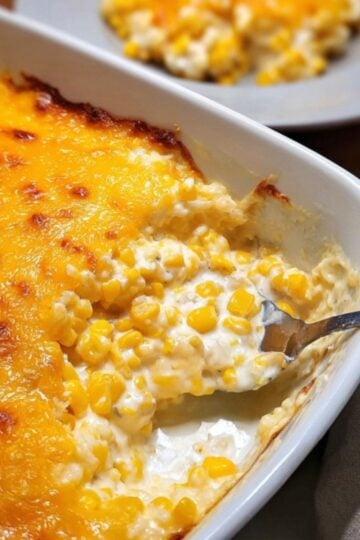 Golden, bubbly baked cream cheese corn casserole being scooped from a baking dish, perfect for Thanksgiving, Christmas, or any comfort food occasion.