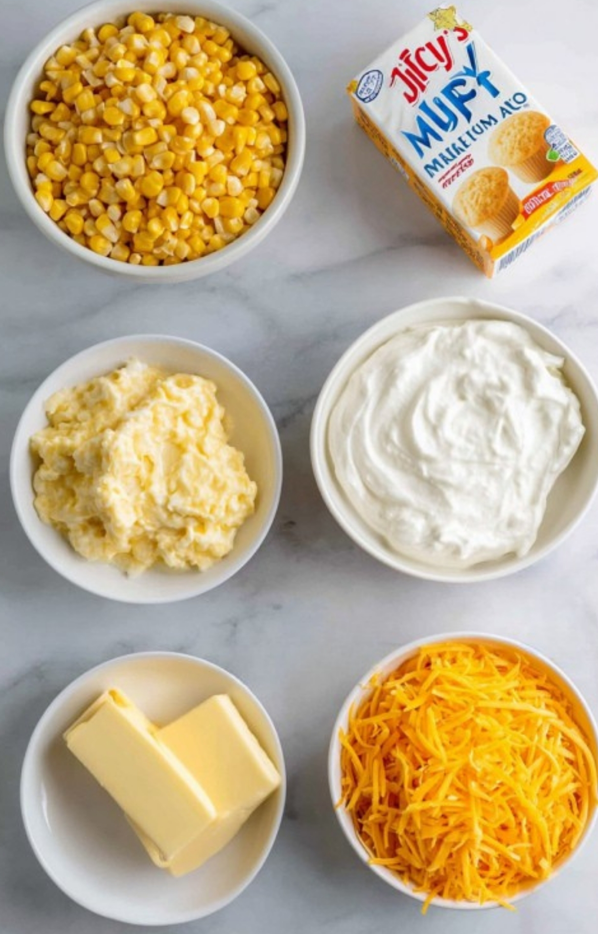 Bowls of corn, cheddar cheese, butter, sour cream, and Jiffy mix lined up for making classic Southern corn casserole