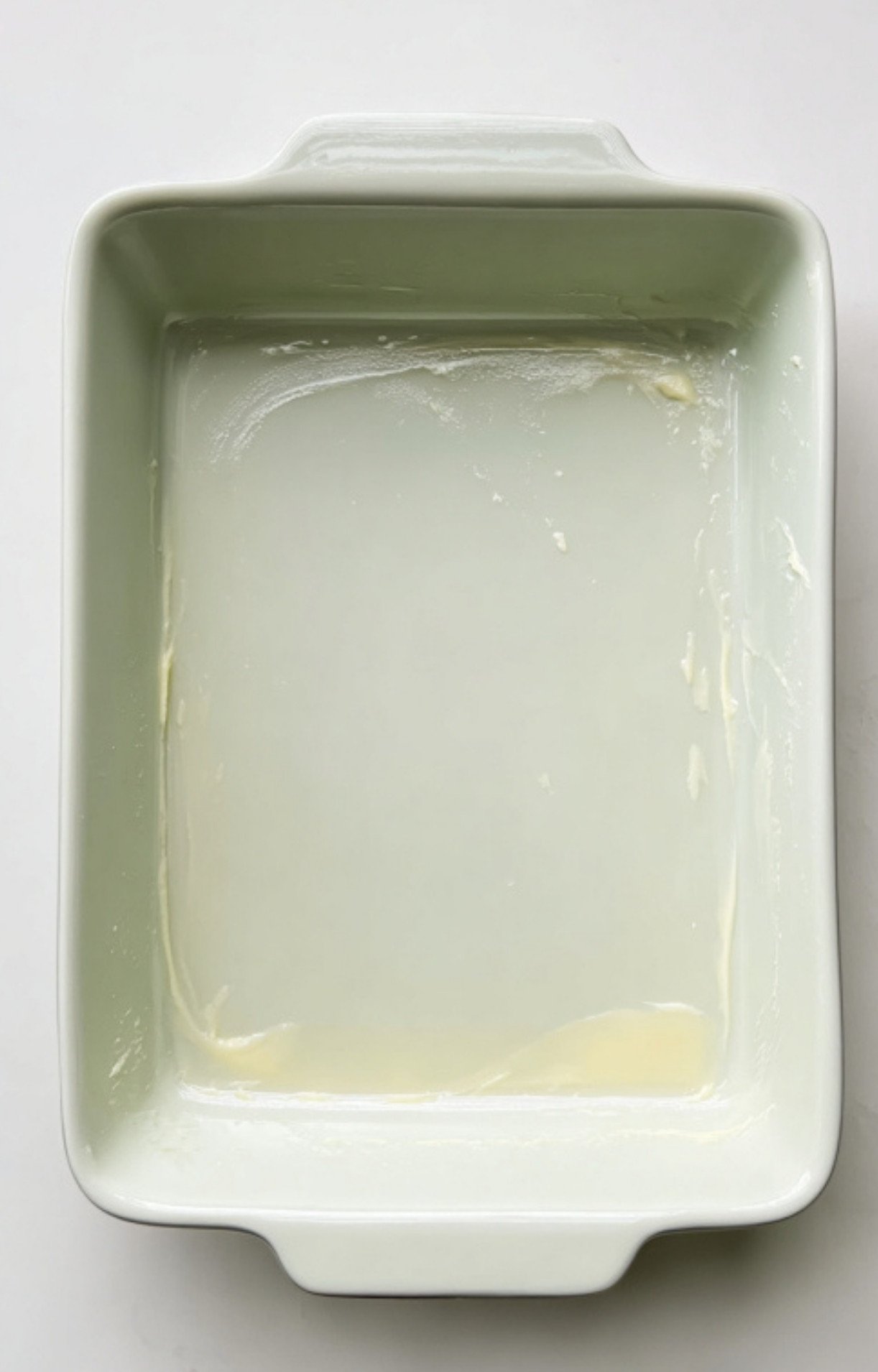 Buttered casserole dish, first step in making scalloped corn casserole, perfect for Thanksgiving meal prep.