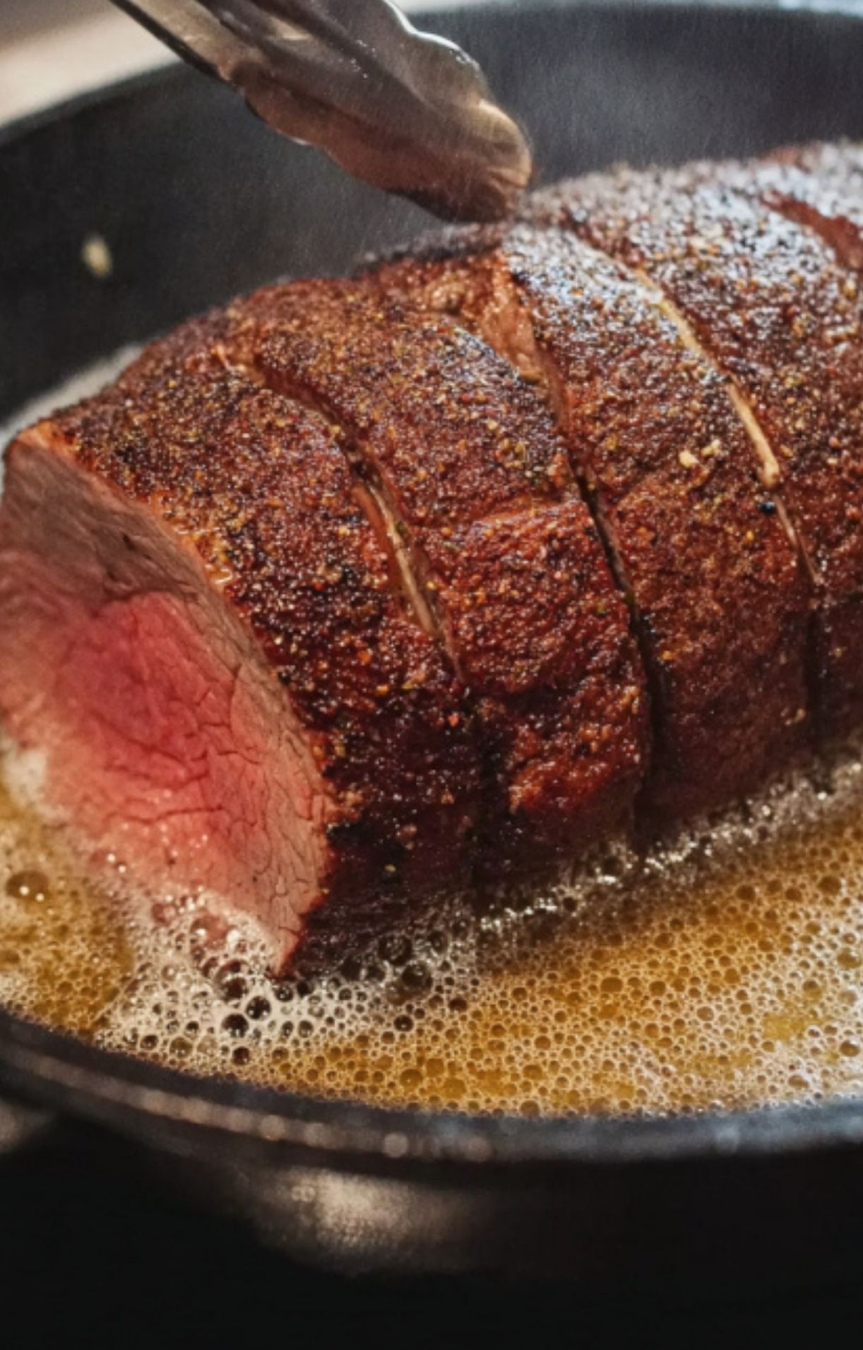 Beef tenderloin being seared in bubbling butter in a skillet, an important step before sous vide for beef wellington.
