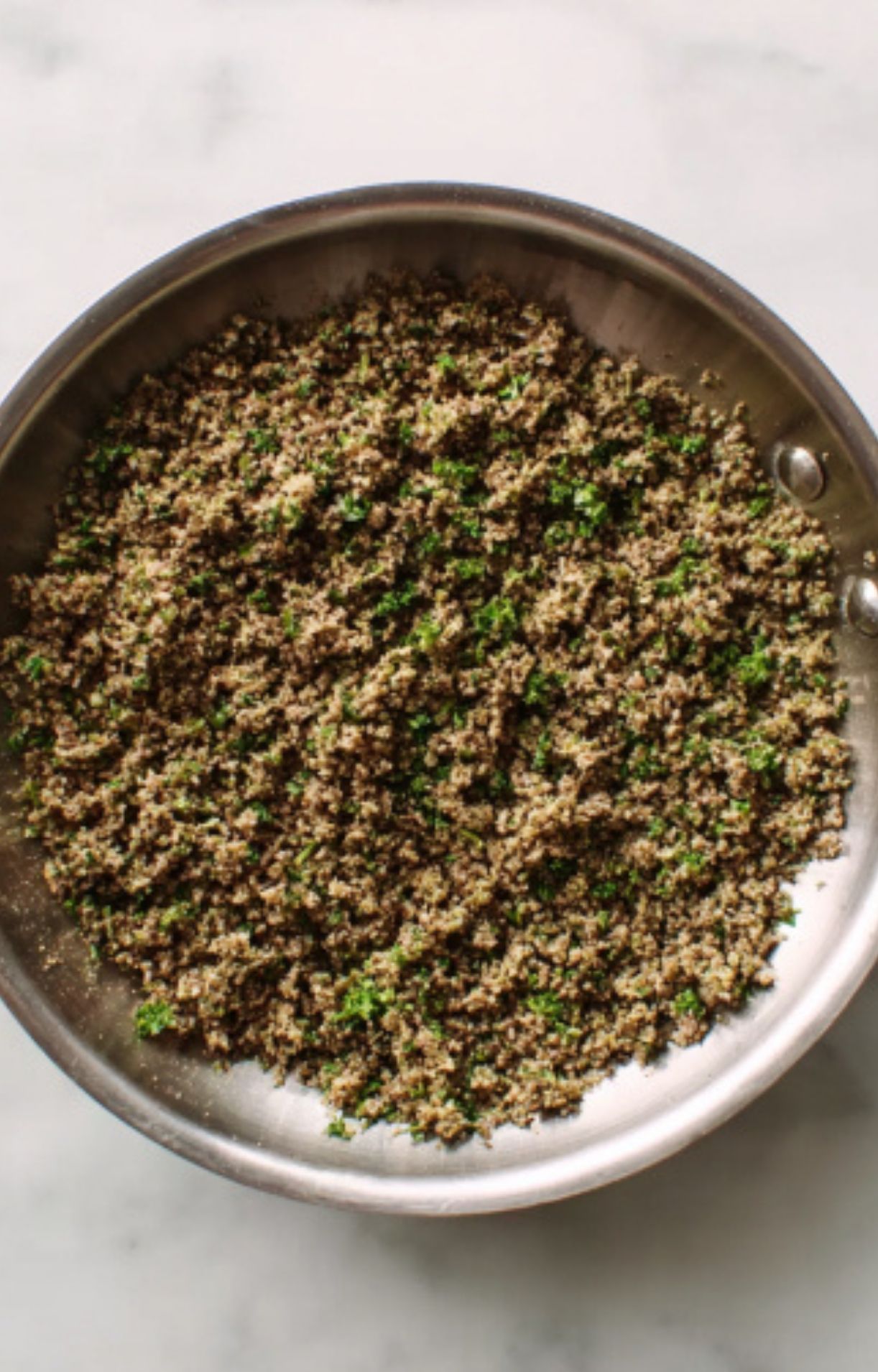 A skillet filled with finely chopped mushroom duxelles and fresh herbs, ready to be used in beef wellington. This savory mixture is essential for an elegant holiday dinner recipe.