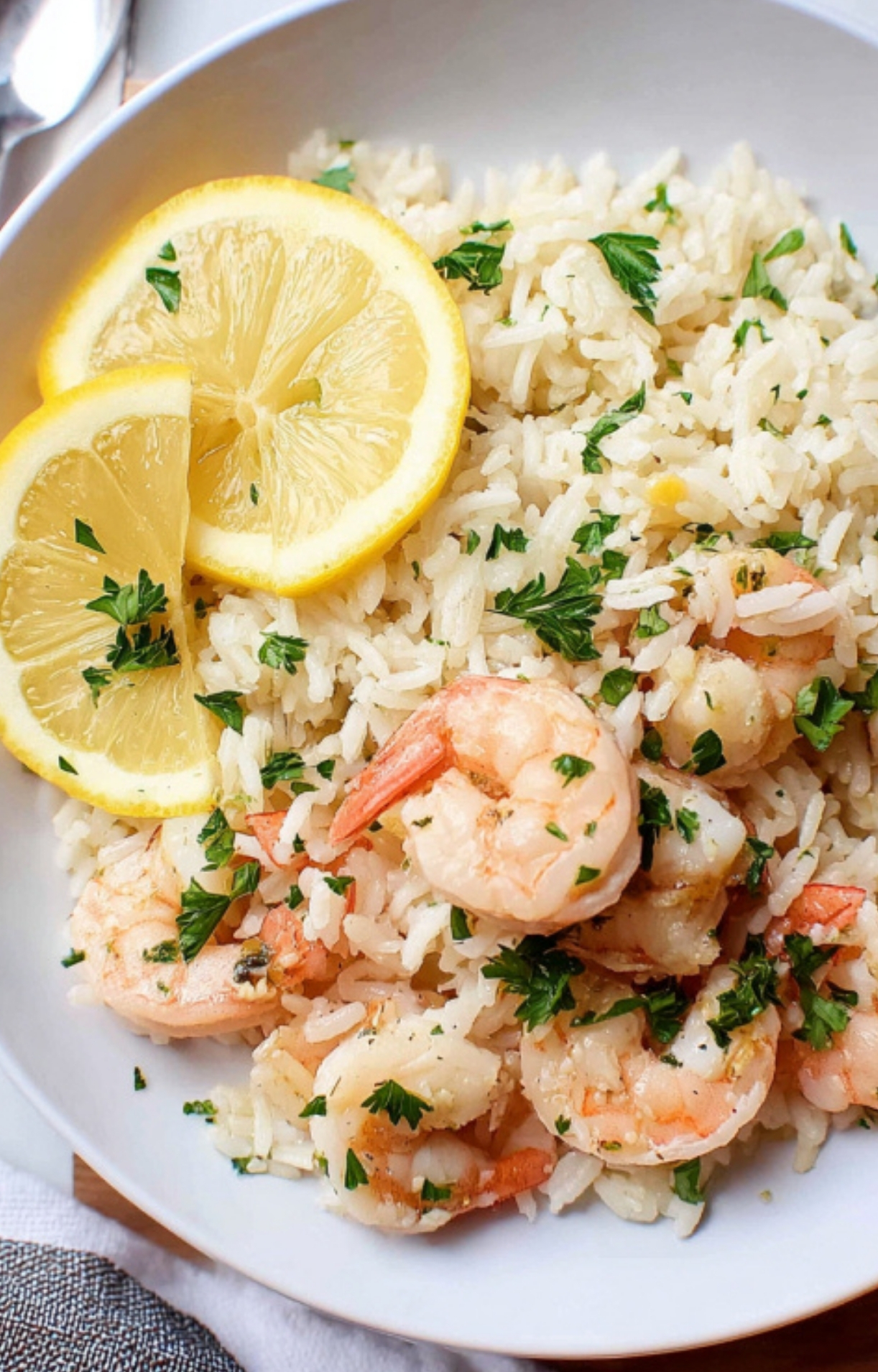 A plate of lemon garlic shrimp and rice garnished with parsley and lemon slices, easy budget meal for families