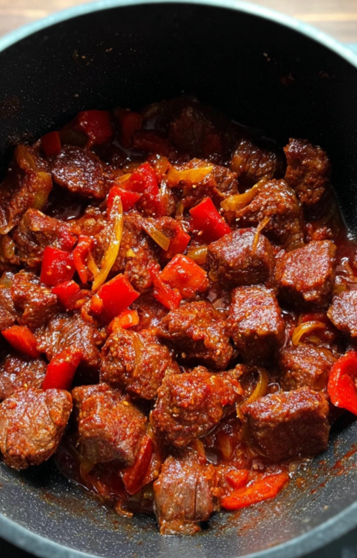 Braised beef, onions, and red peppers in a rich sauce, getting ready for the slow cooker. Classic step for Hungarian goulash.