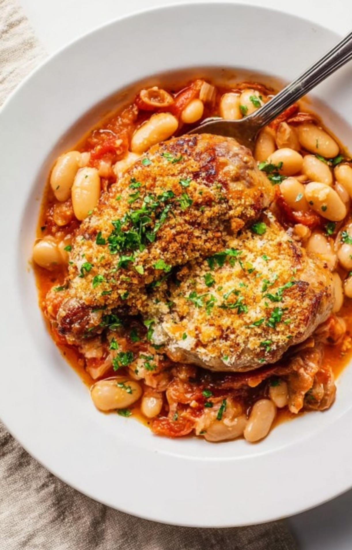 Bowl of cassoulet with juicy chicken, beans, and sausage, finished with crunchy breadcrumbs and fresh parsley for a simple comfort meal.
