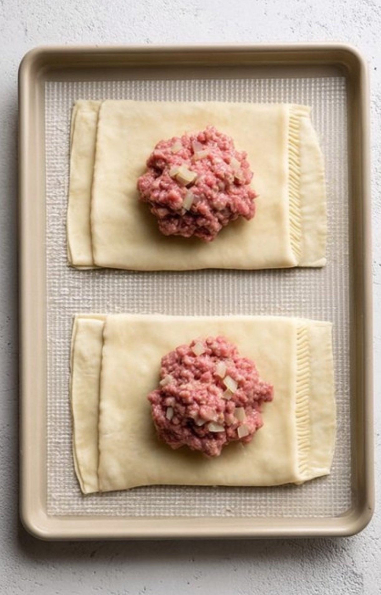 Plated ground beef Wellington topped with creamy mushroom sauce and fresh parsley, perfect for dinner parties.