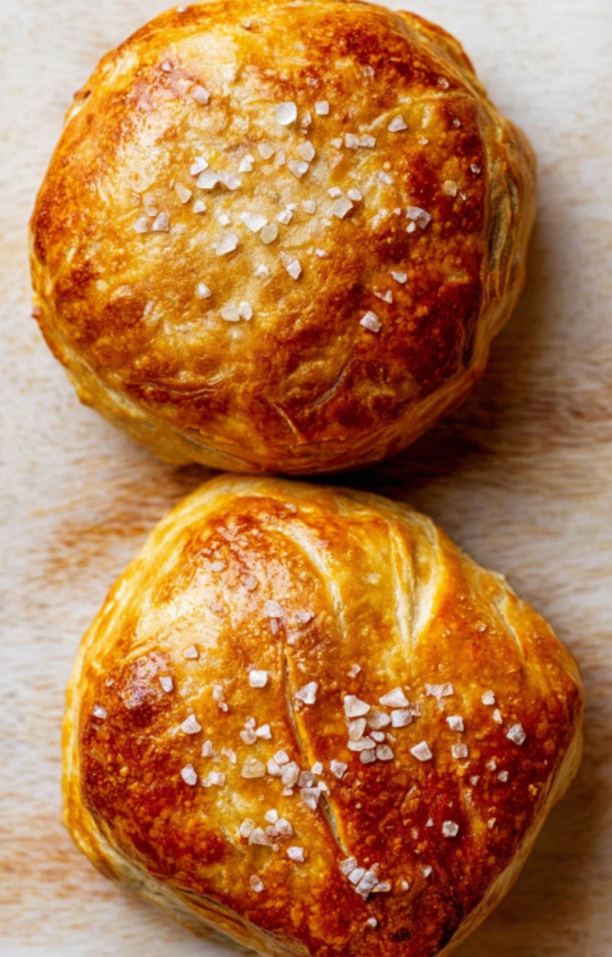 Two individual beef Wellington parcels baked golden brown and topped with flaky sea salt, perfect for a romantic dinner or special celebration.