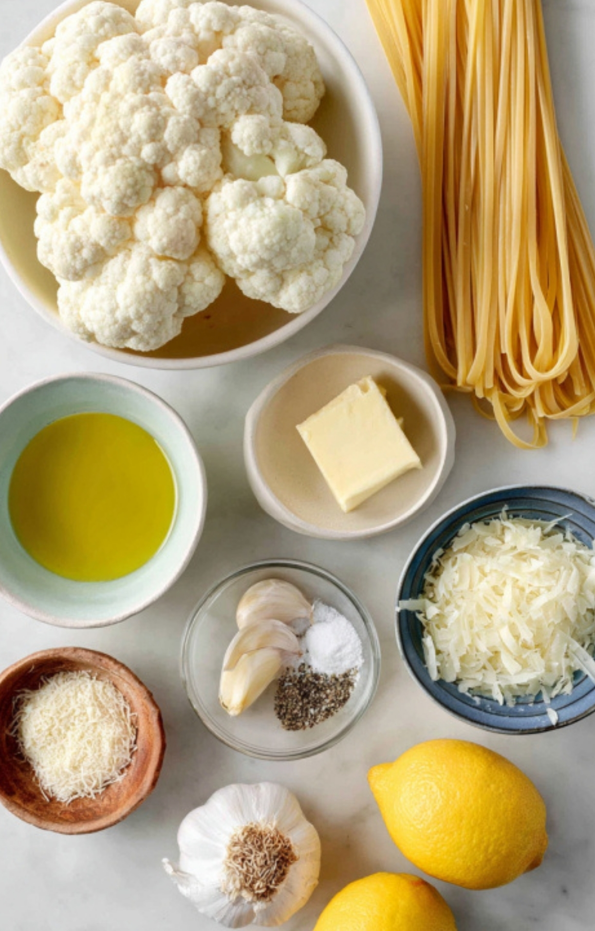 Flat lay of fresh cauliflower, pasta, olive oil, garlic, butter, Parmesan, lemon, and seasonings, all set for an easy 30 minute meal.