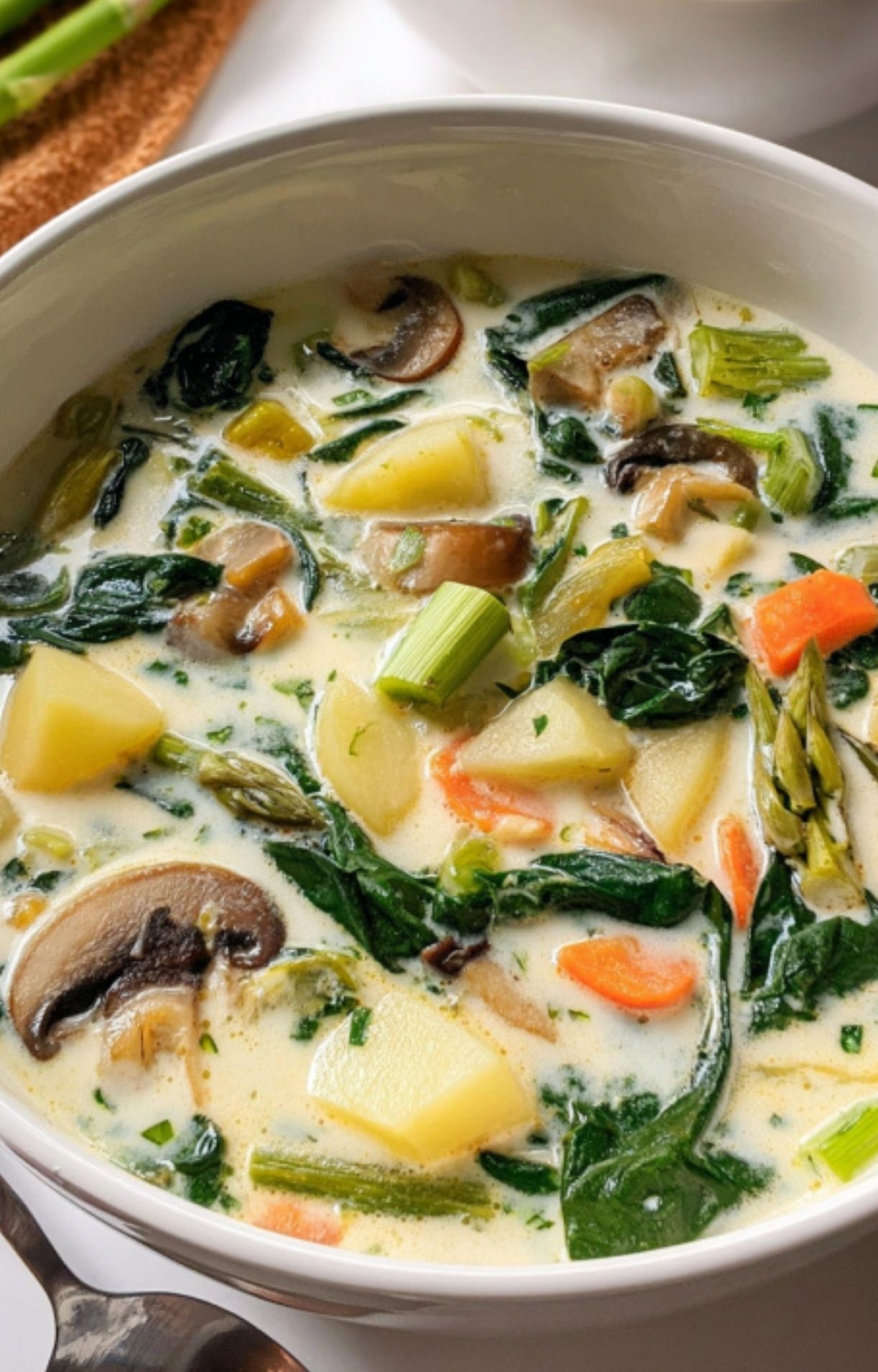 A bowl of French spring soup featuring creamy broth, potatoes, spinach, carrots, asparagus, and mushrooms. A family-friendly, gluten-free meal for soup lovers.