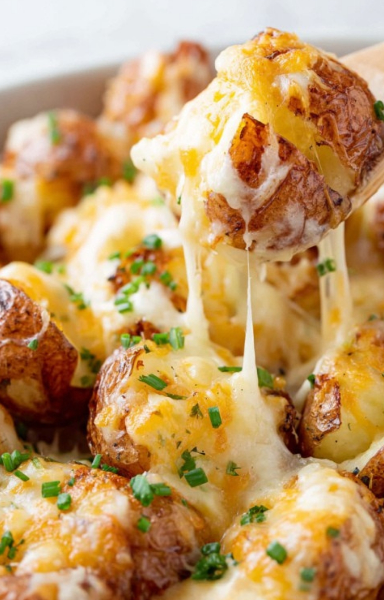 Close up of cheesy ranch potatoes with gooey melted cheese and fresh chives, perfect for a family dinner or potluck side.