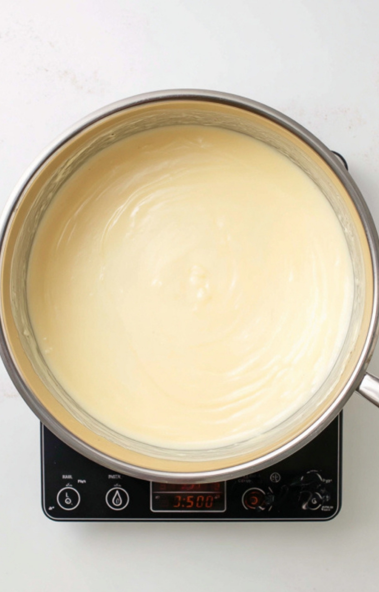 Pot of silky smooth cream cheese sauce prepared for mixing with corn, the secret to a luscious corn casserole.