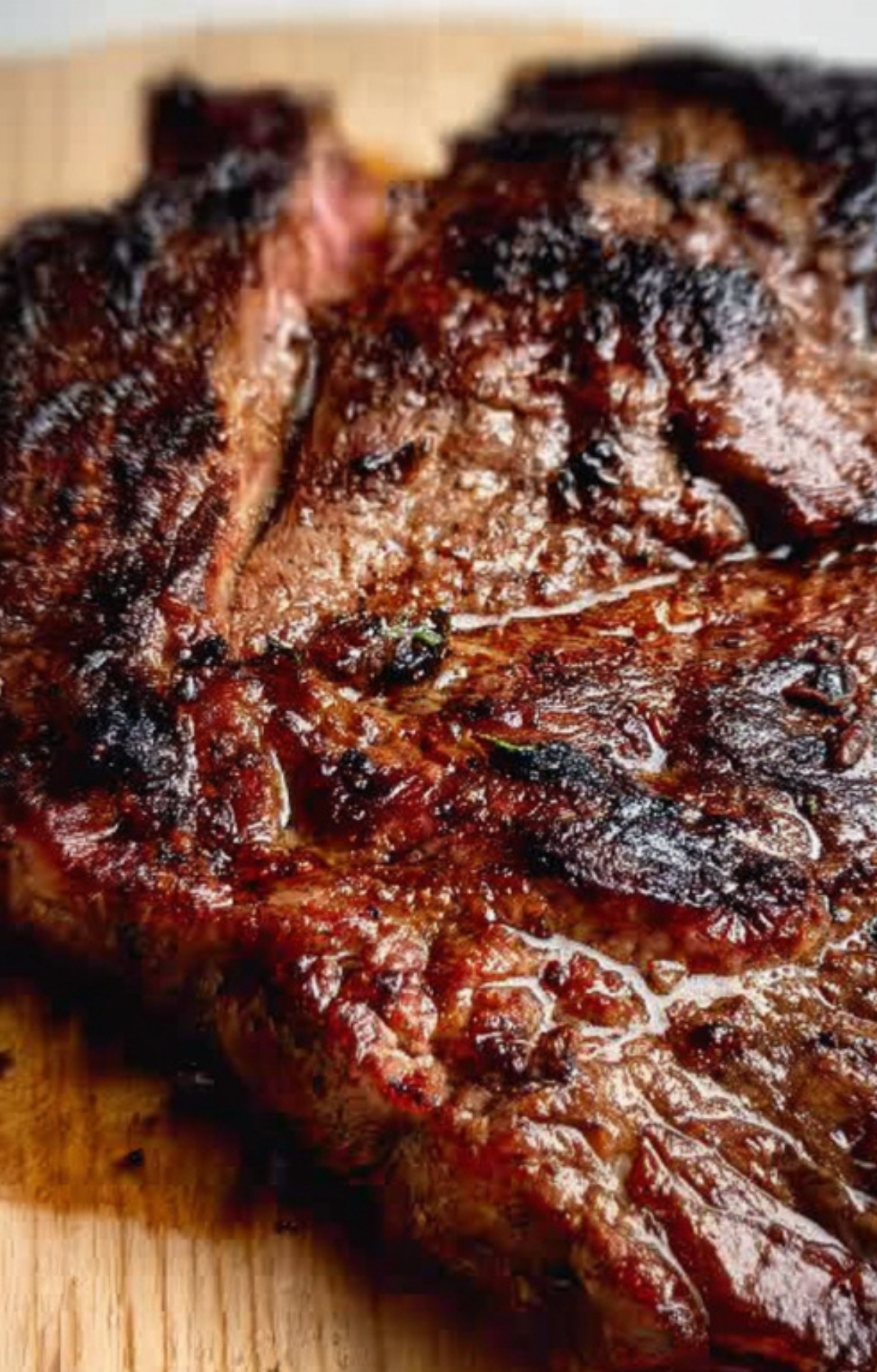 Cooked steak resting on a wooden cutting board, locking in juices for a tender, restaurant-style steak meal