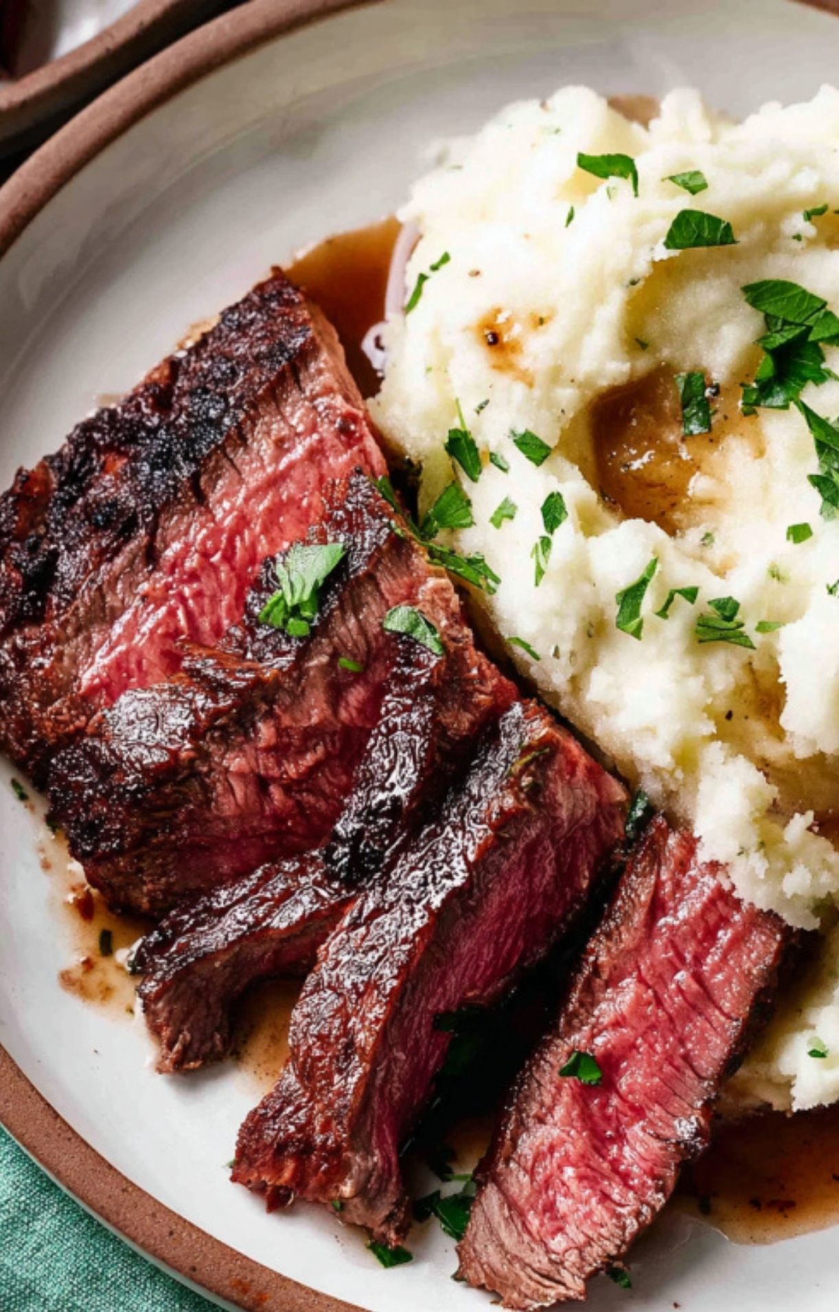 Tender sliced chuck steak served with creamy mashed potatoes and fresh herbs for a classic steak dinner
